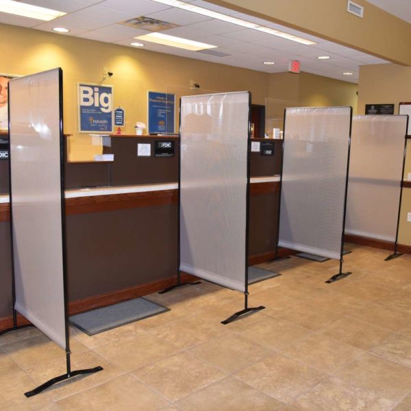 Several semi-transparent social distancing partition barriers used for customer service lines.